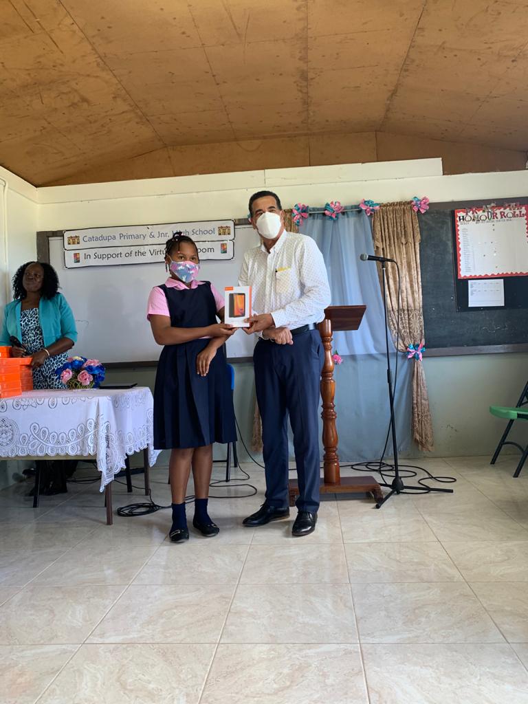 Member of Parliament for Southern St. James The Honorable Homer Davis, handing one of the tablets to a Student of the Catadupa Primary School 